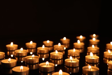 Photo of Burning candles on mirror surface in darkness