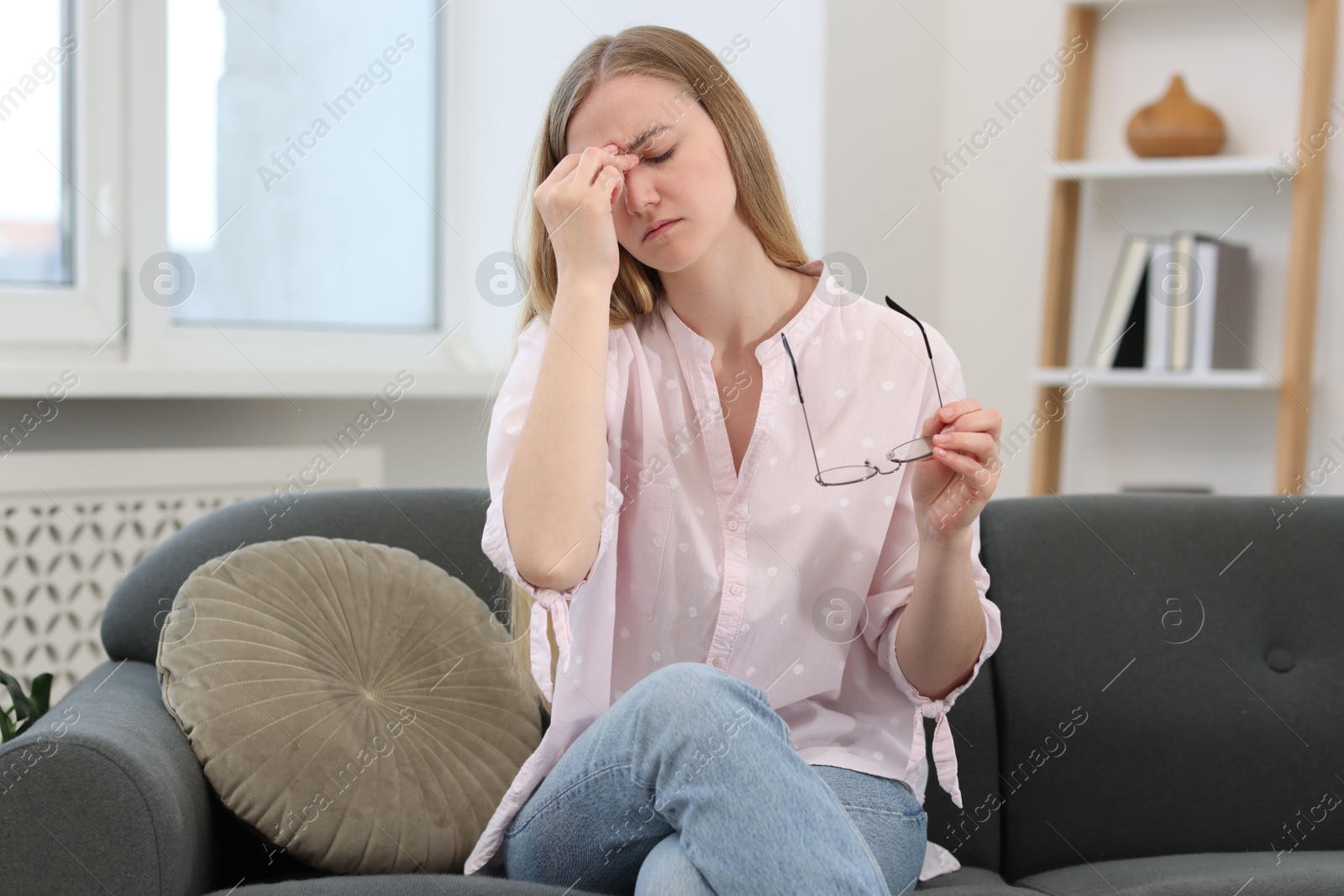Photo of Overwhelmed young woman with glasses suffering from headache at home