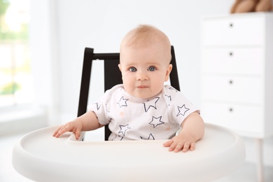 Photo of Cute little baby in high chair at home