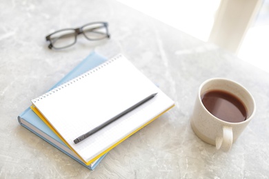 Photo of Notebooks, coffee and pencil on grey marble table, space for text