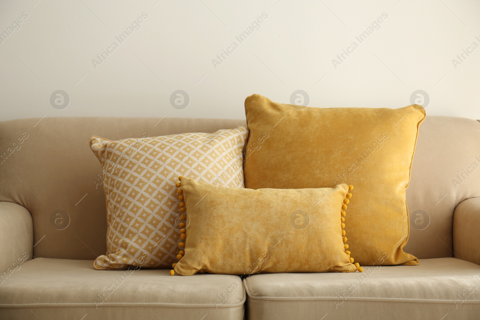 Image of Three pillows on sofa near wall in room. Interior design