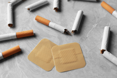 Photo of Nicotine patches and broken cigarettes on grey table