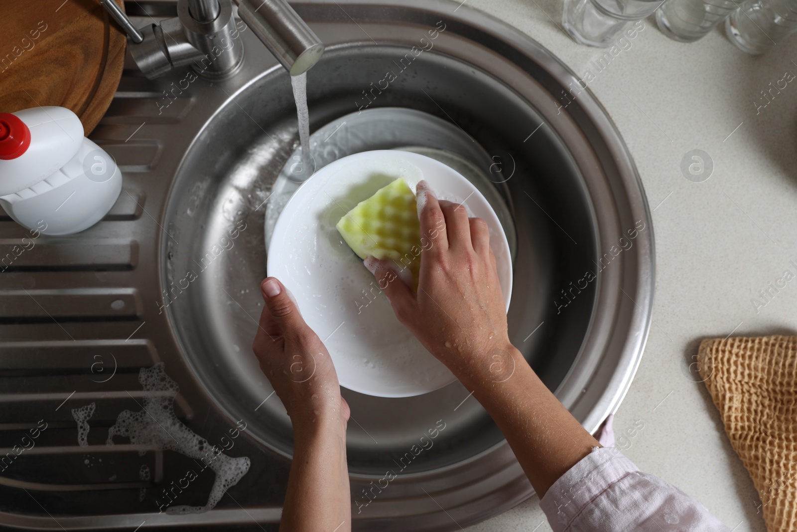 Photo of Woman washing plate in kitchen sink, above view