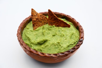 Photo of Delicious guacamole made of avocados with nachos on white background, closeup