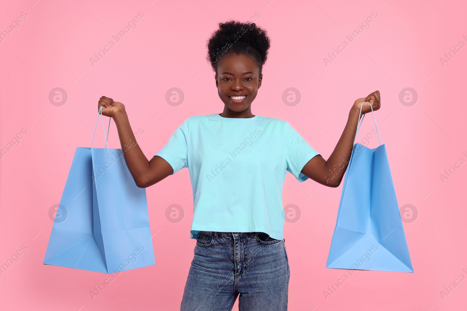 Photo of Happy young woman with shopping bags on pink background