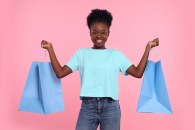 Photo of Happy young woman with shopping bags on pink background