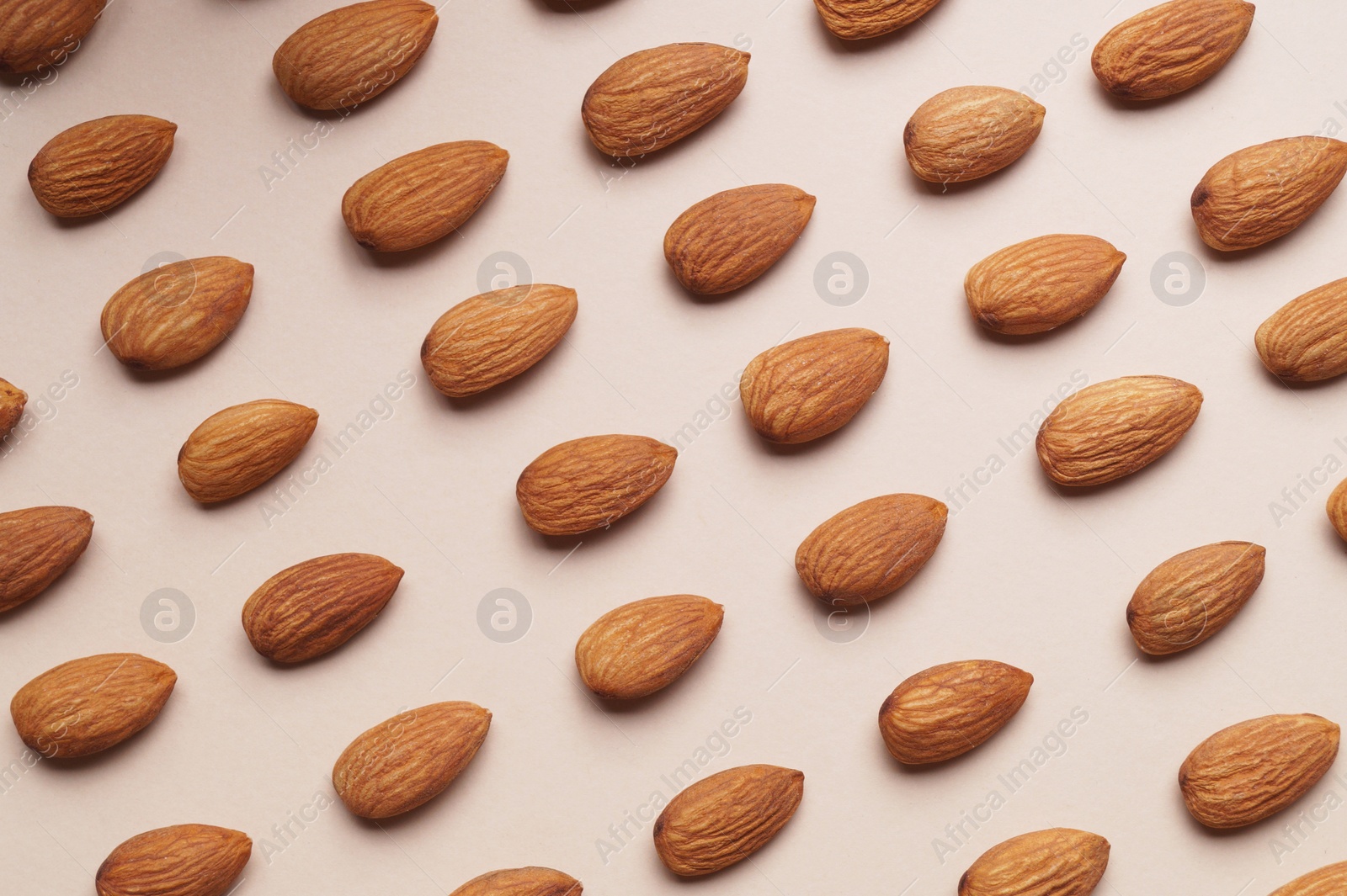 Photo of Delicious raw almonds on beige background, flat lay