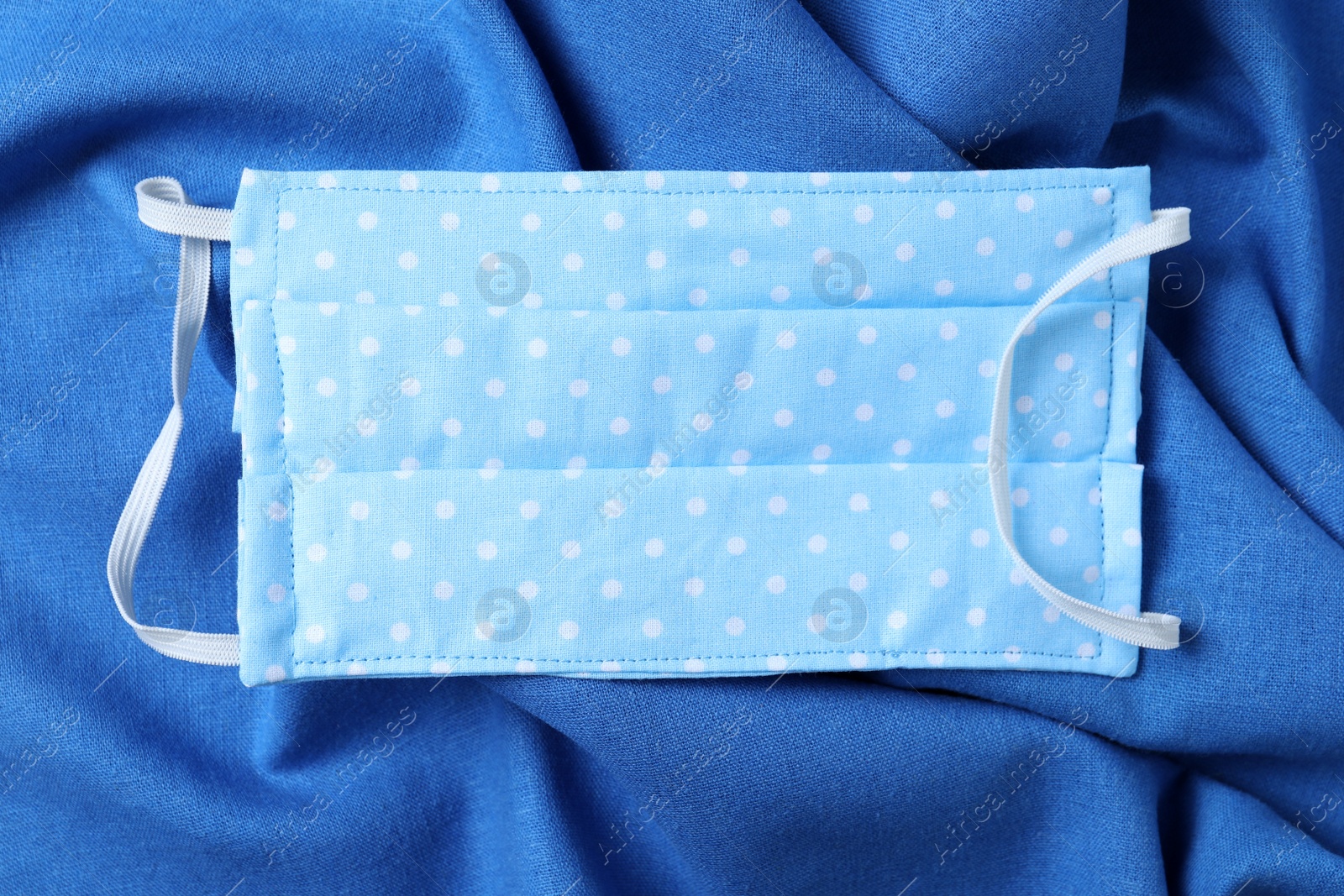 Photo of Homemade protective mask on blue fabric, top view