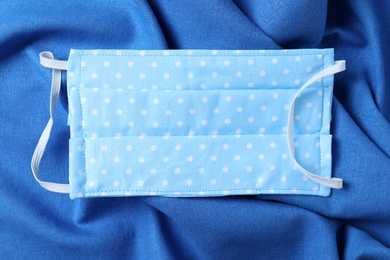 Photo of Homemade protective mask on blue fabric, top view