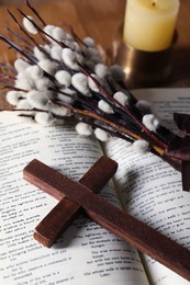 Wooden cross, Bible and willow branches on table