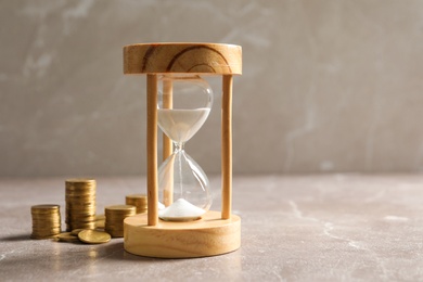 Photo of Hourglass and coins on table. Time management