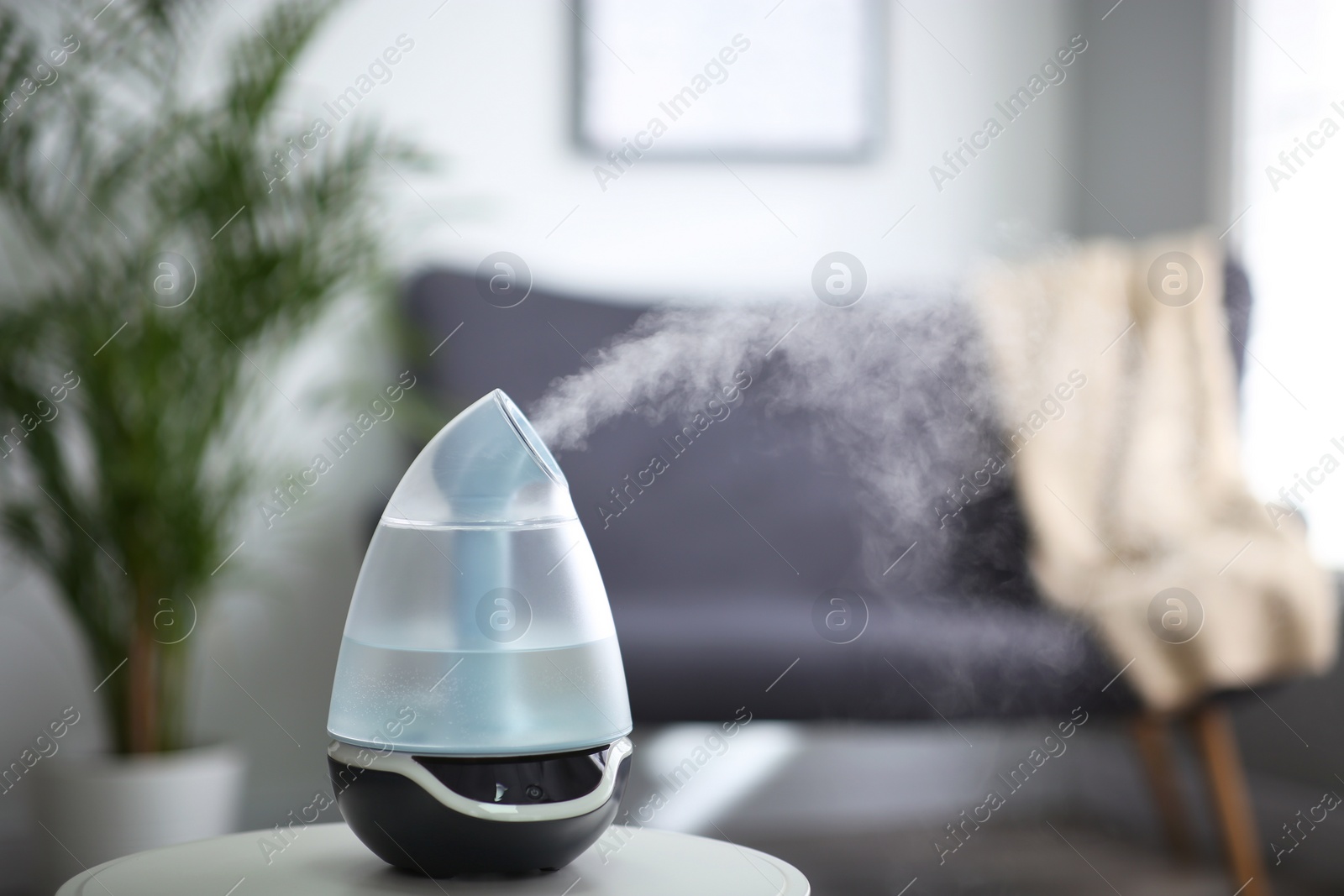 Photo of Modern air humidifier on table indoors. Space for text