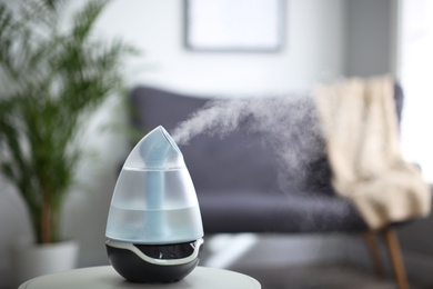 Photo of Modern air humidifier on table indoors. Space for text