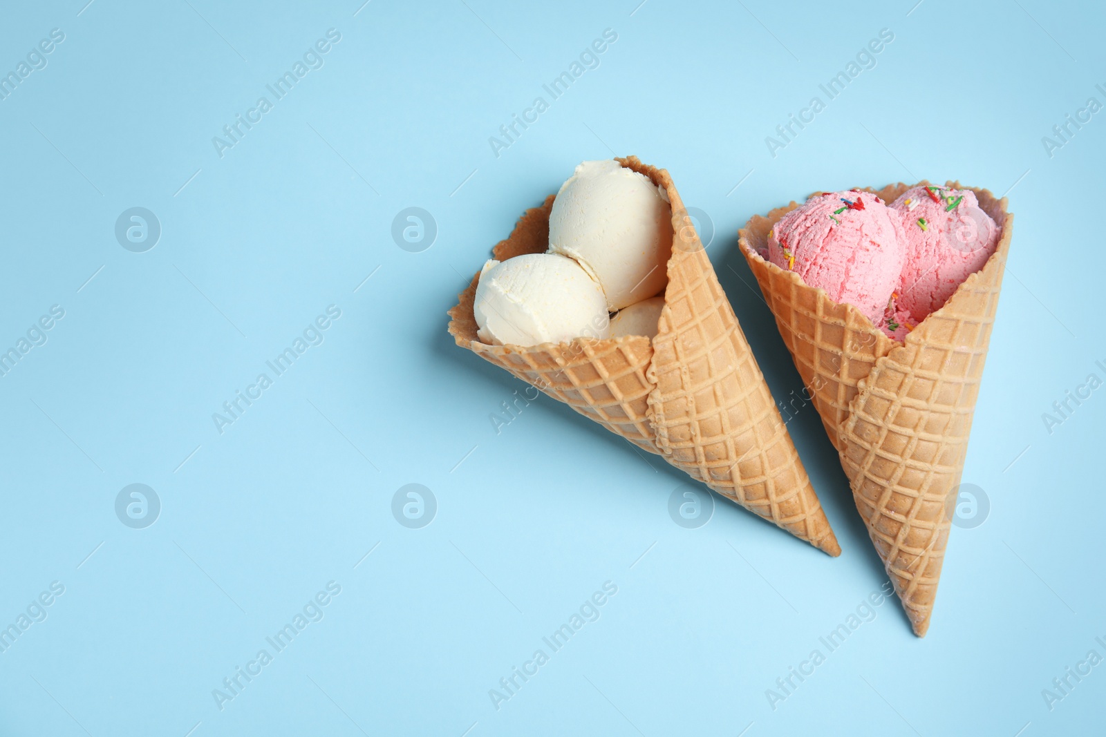 Photo of Delicious ice creams in wafer cones on blue background, flat lay. Space for text