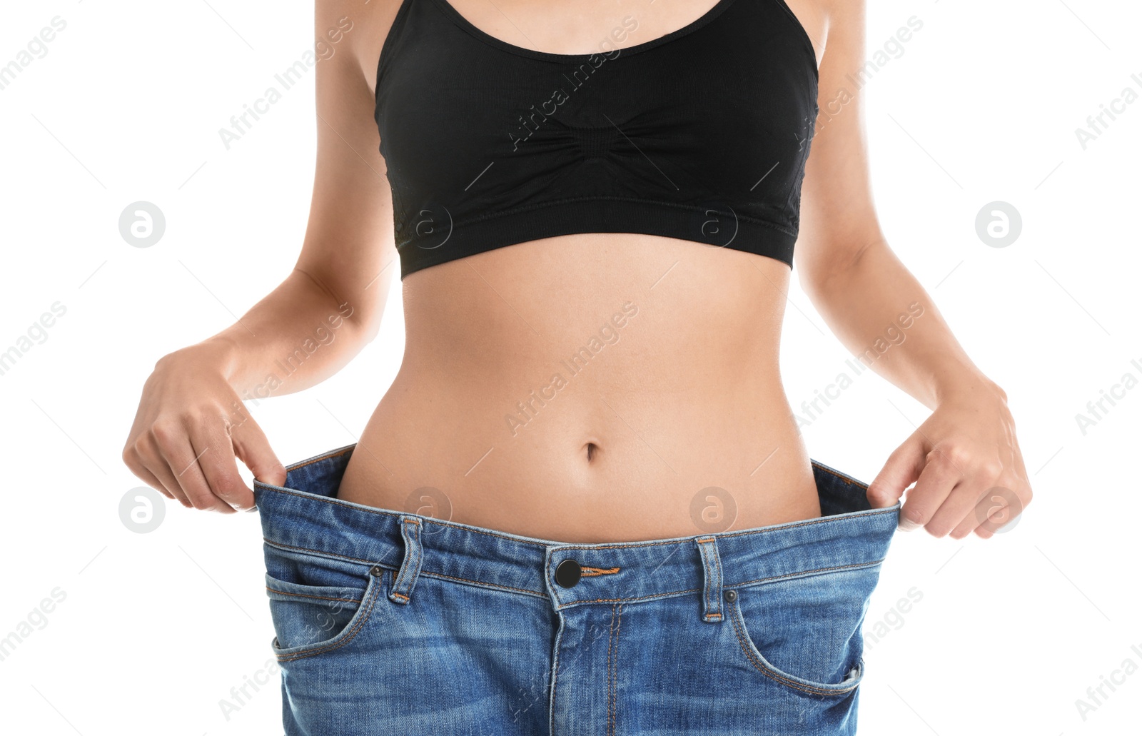 Photo of Young woman with slim body wearing her old big jeans on white background, closeup