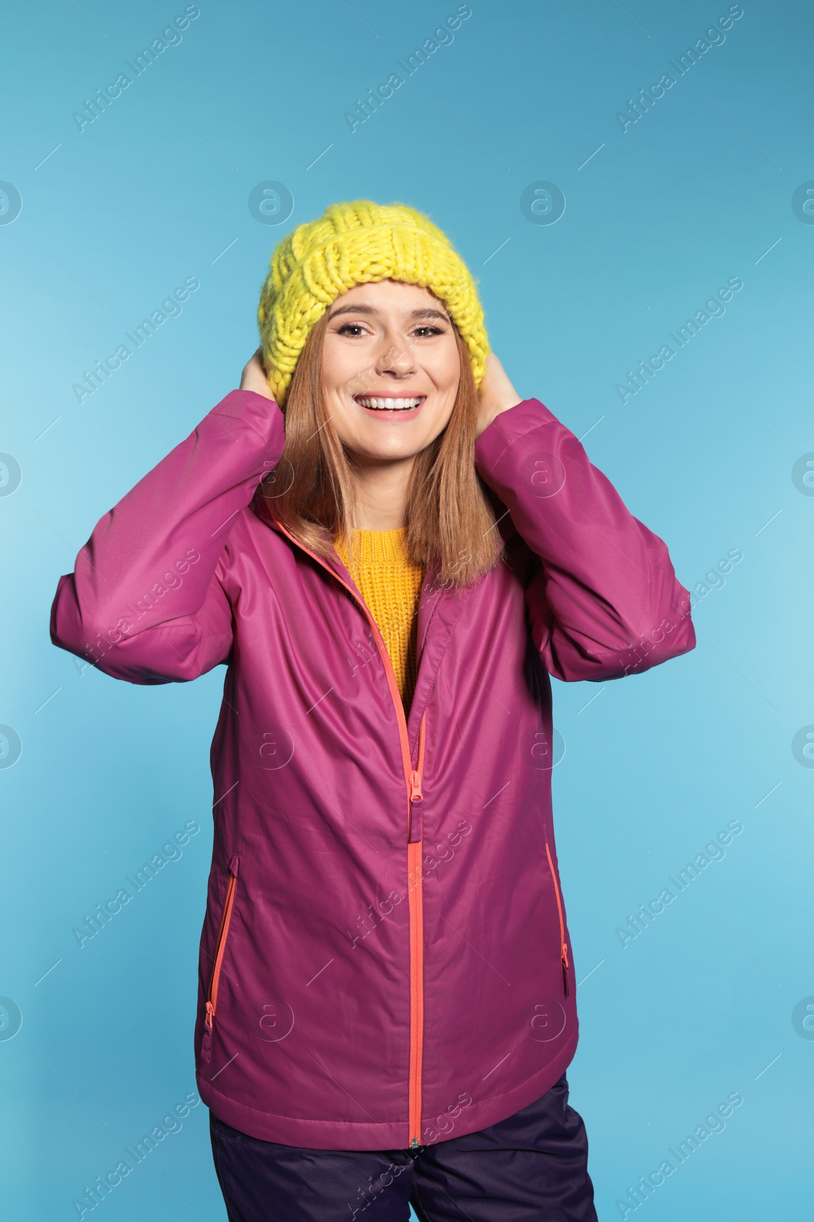 Photo of Young woman wearing warm clothes on color background. Ready for winter vacation