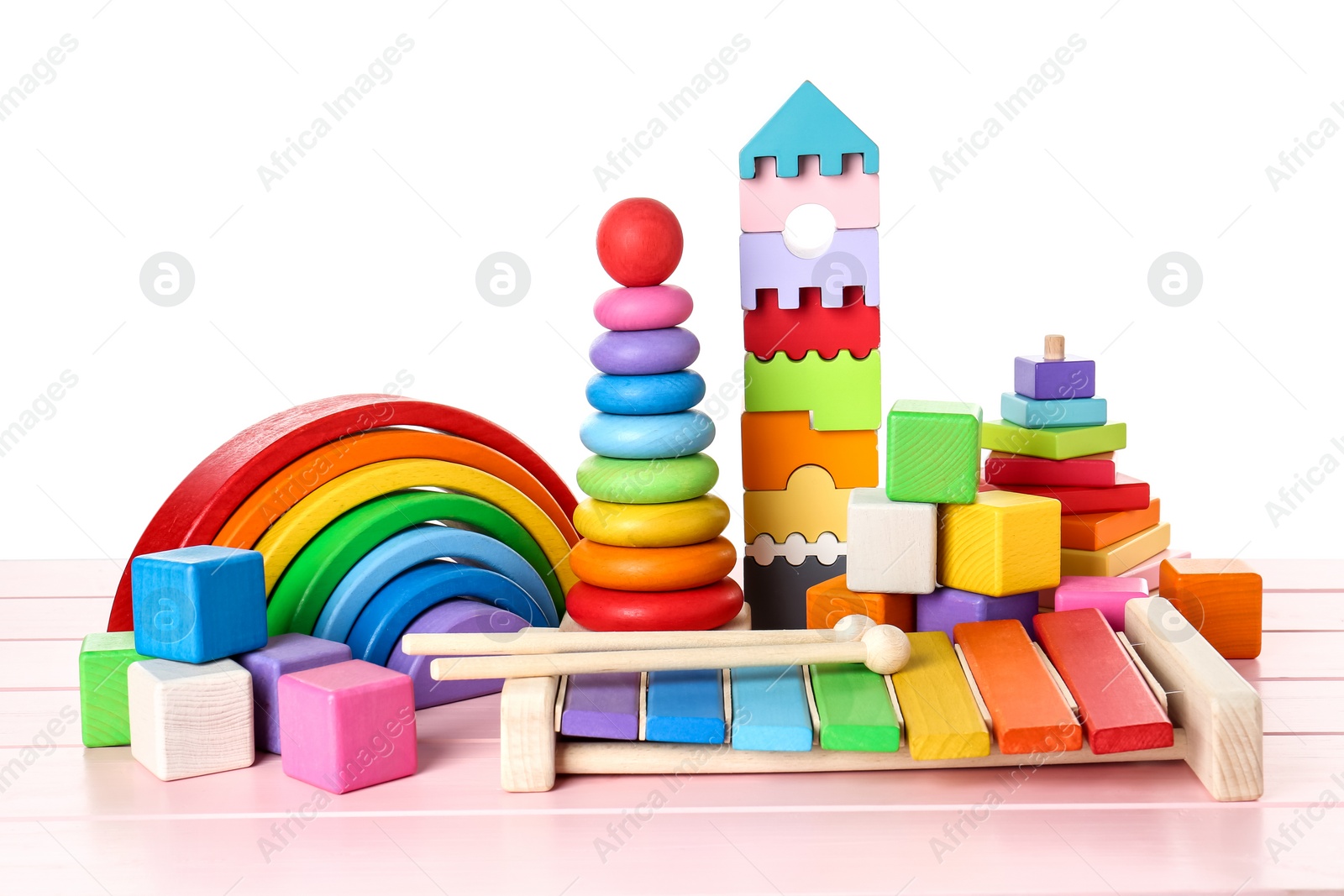 Photo of Different children's toys on pink wooden table against white background