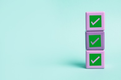 Image of Stacked cubes with check marks on turquoise background. Space for text