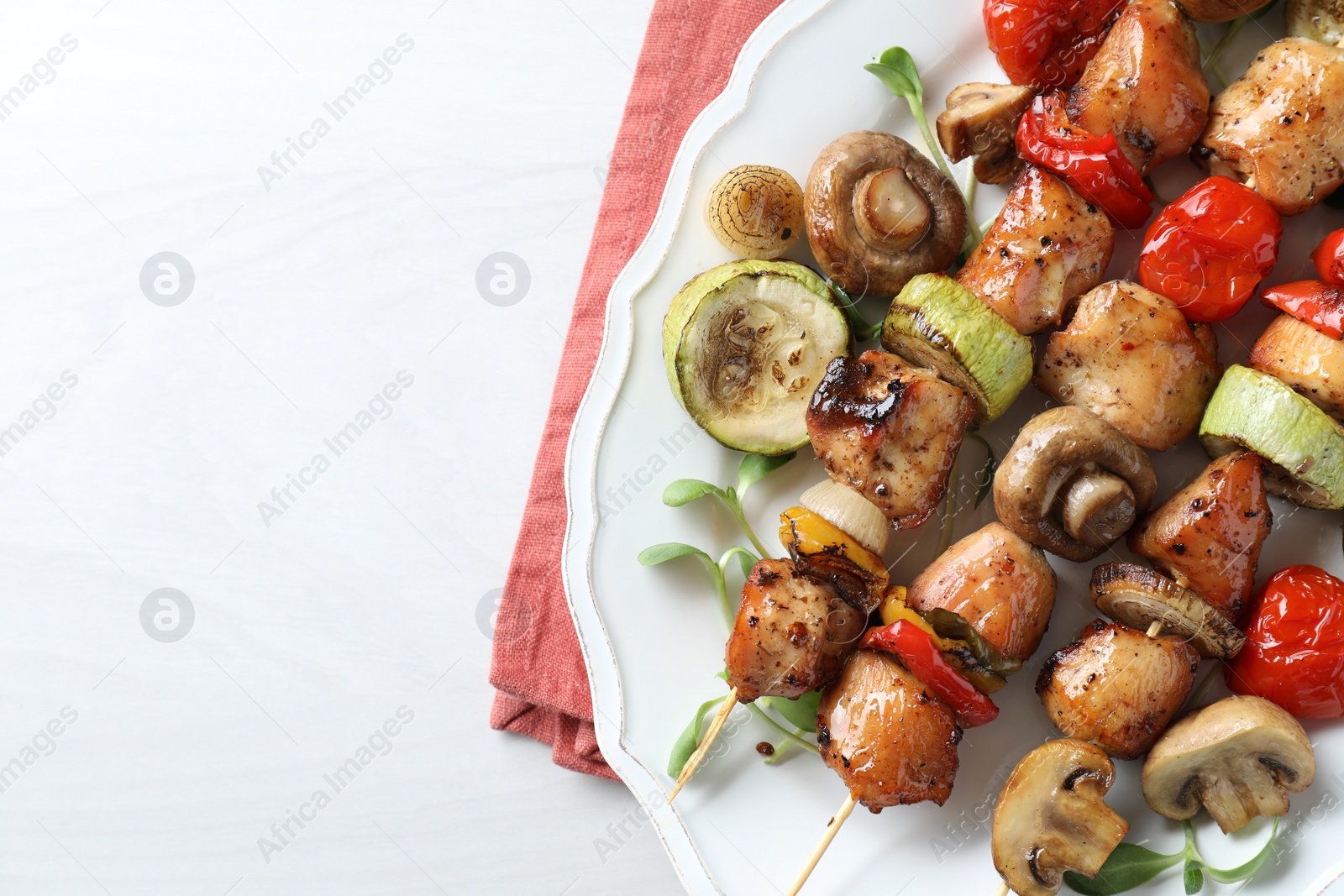 Photo of Delicious shish kebabs with vegetables and microgreens on white table, top view. Space for text