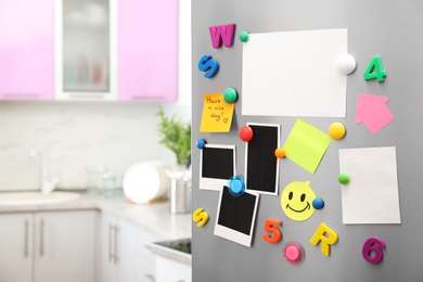 Photo of Sheets of paper and photos with colorful magnets on refrigerator door in kitchen. Space for text