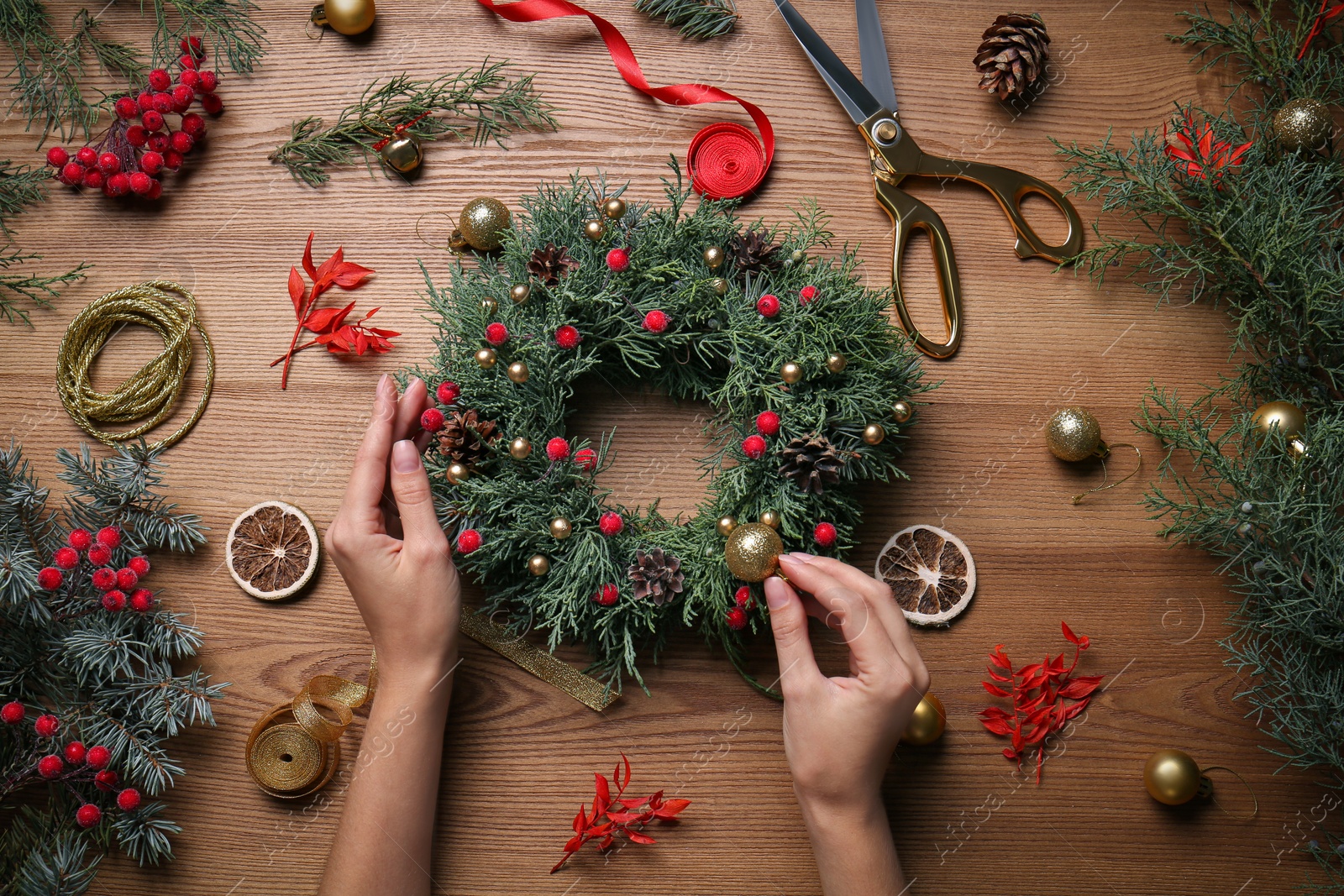 Photo of Florist making beautiful Christmas wreath at wooden table, top view