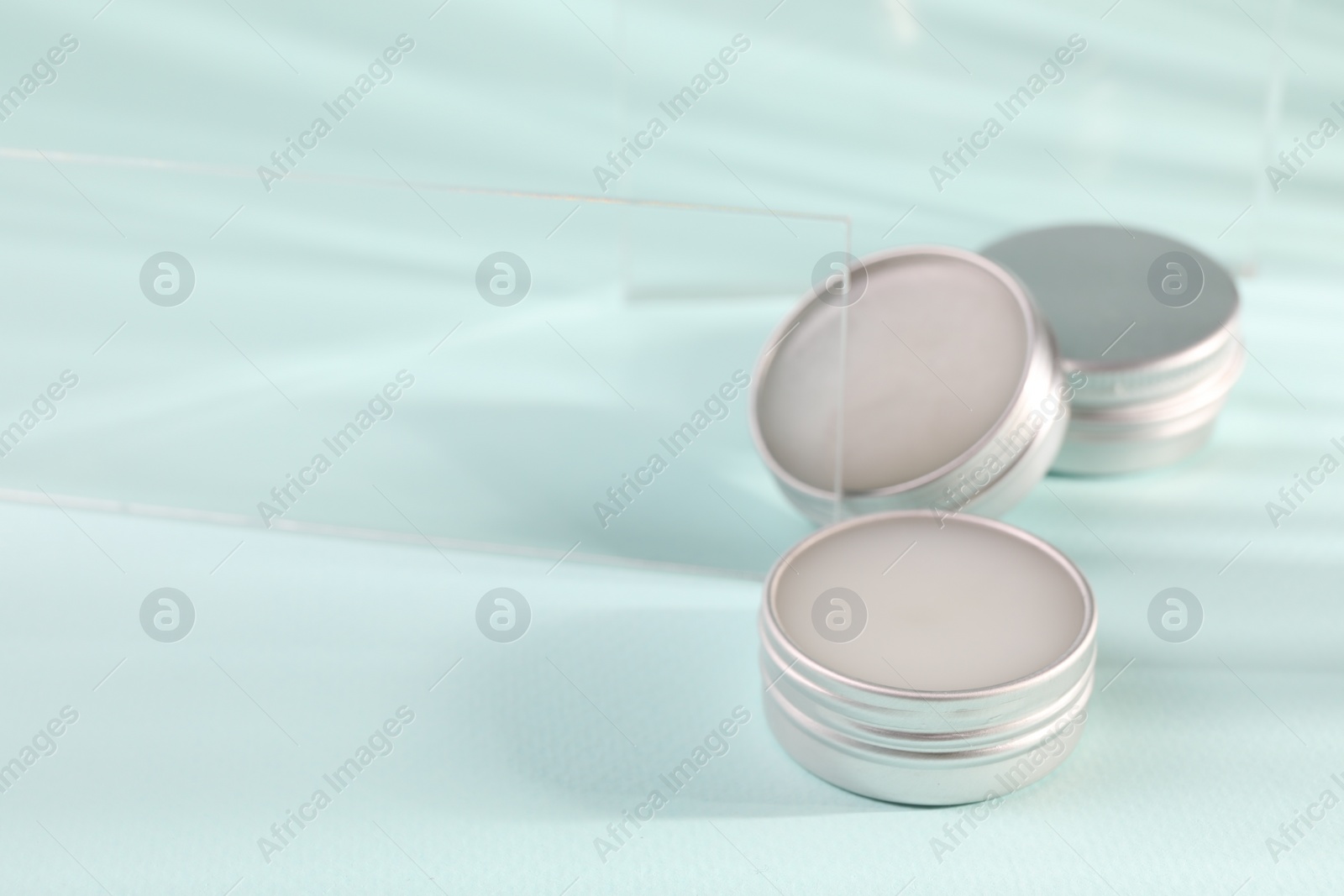 Photo of Lip balms on light blue background, space for text