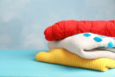 Photo of Stack of folded knitted sweaters on table. Space for text