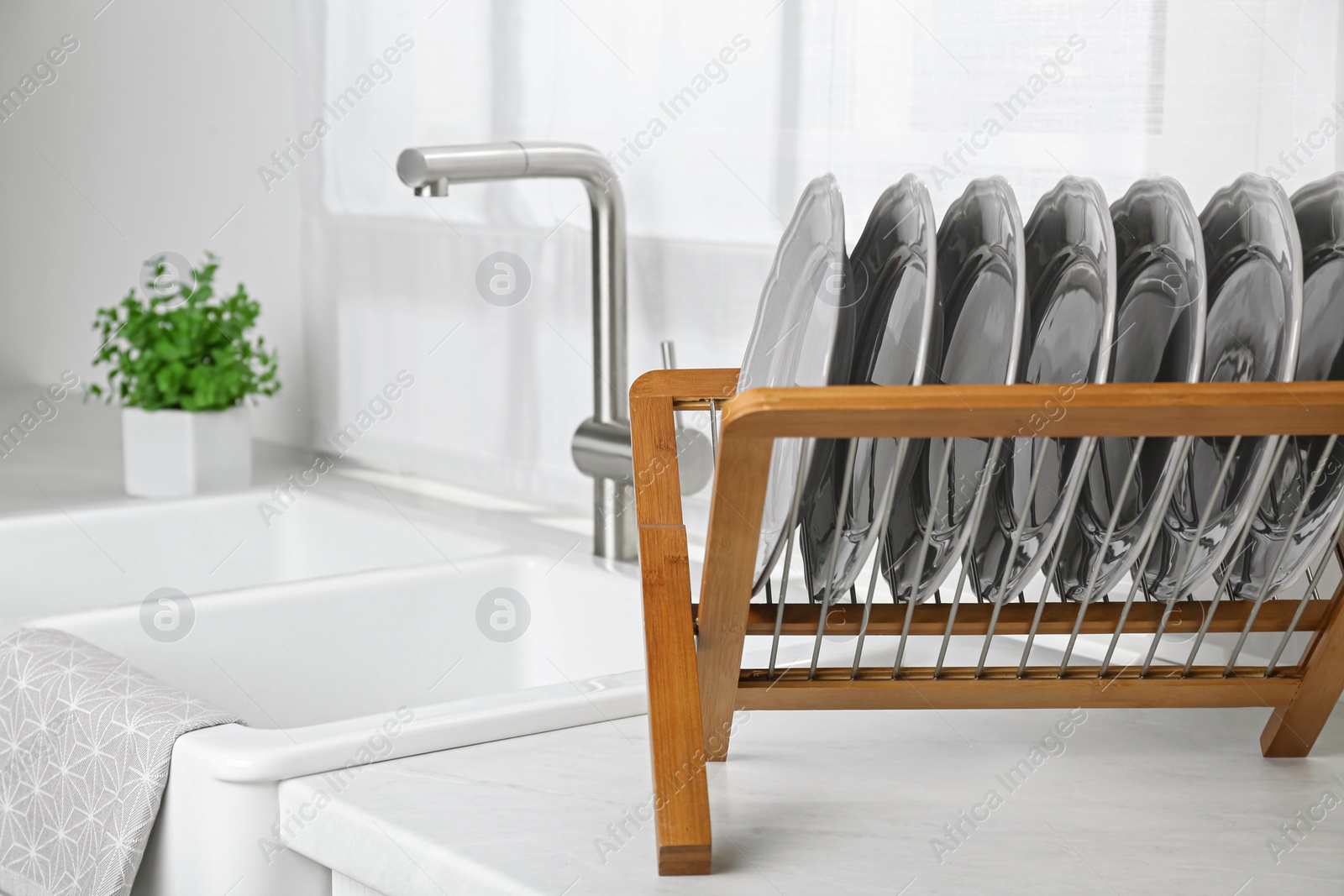 Photo of Wooden holder with grey plates on countertop near sink in kitchen