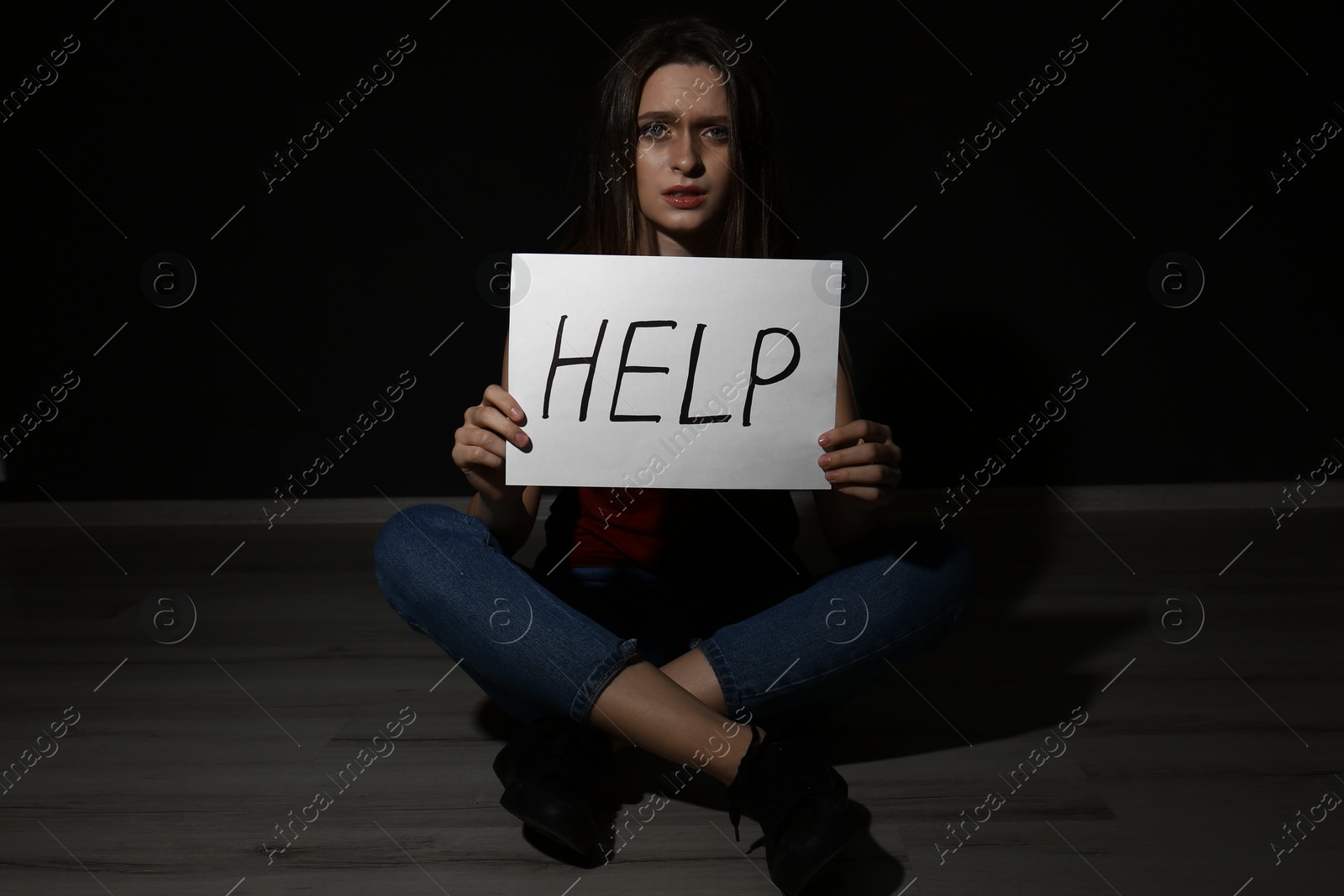 Photo of Abused young woman with sign HELP on black background. Domestic violence concept