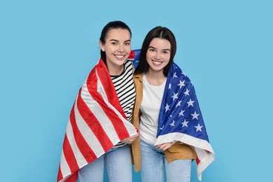 Photo of 4th of July - Independence Day of USA. Happy woman and her daughter with American flag on light blue background