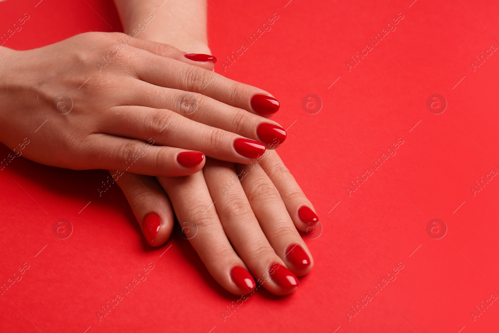 Photo of Woman with gel polish on nails on red background, closeup. Space for text