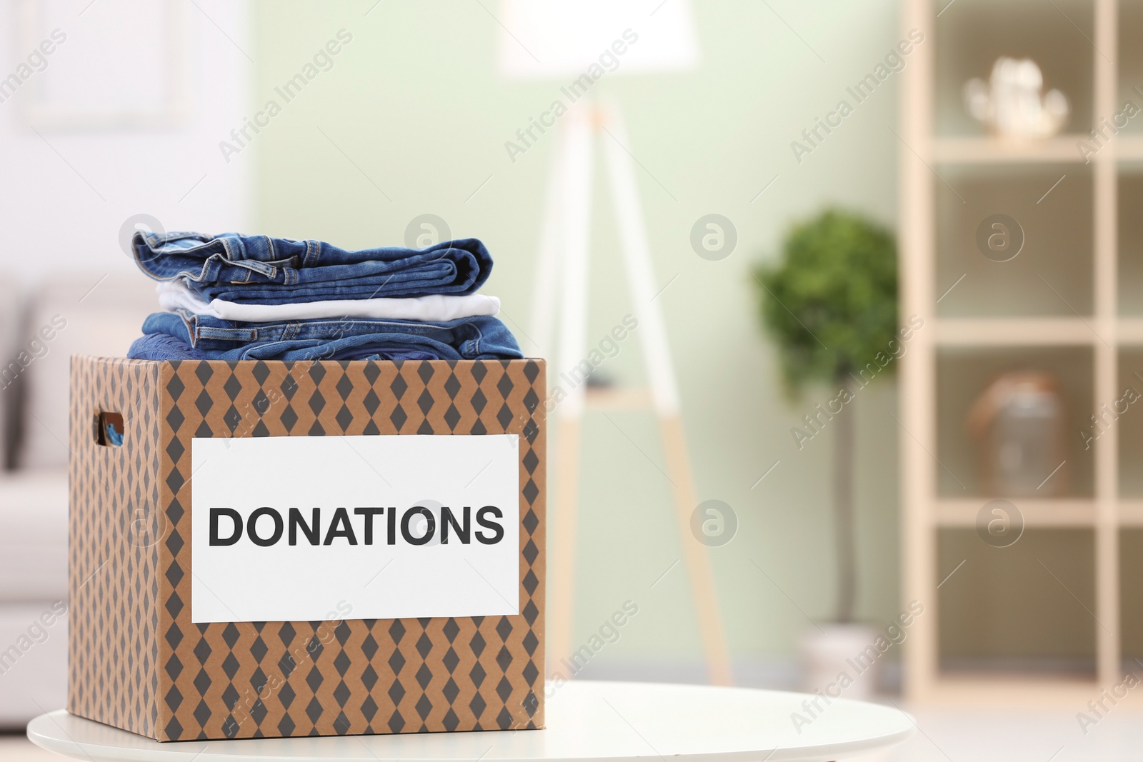 Photo of Donation box with clothes on table indoors