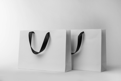 Photo of Paper shopping bags with ribbon handles on white background. Mockup for design