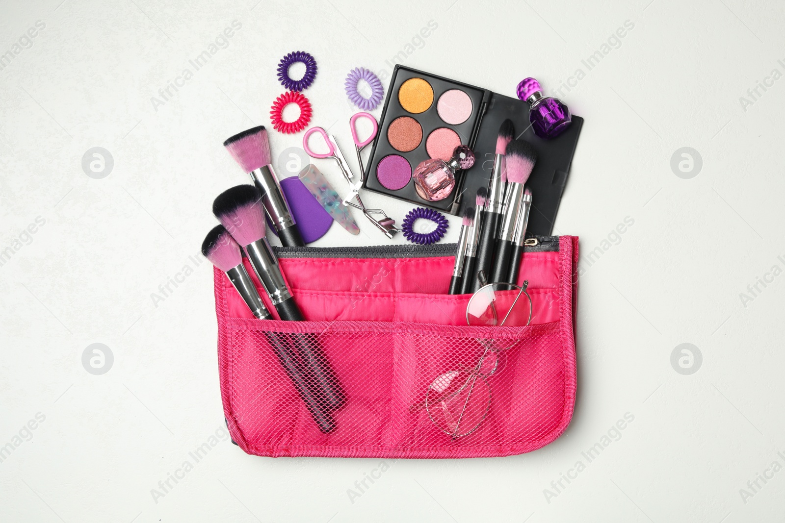 Photo of Cosmetic bag with makeup products and beauty accessories on white background, flat lay