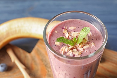 Photo of Glass with blueberry smoothie on table, closeup