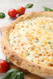 Photo of Delicious cheese pizza, basil and tomatoes on light grey table, closeup