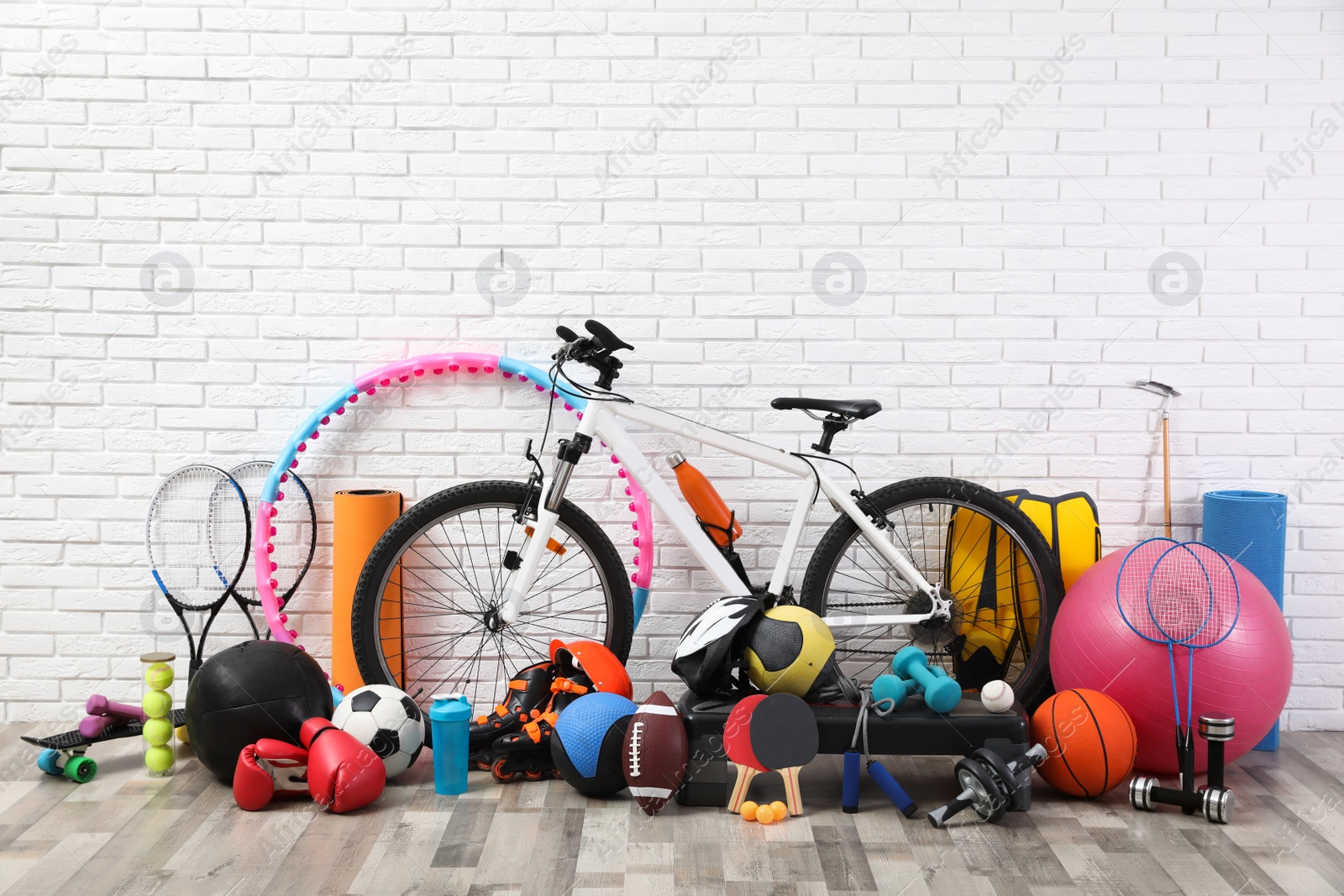 Photo of Bicycle and different sport equipment near white brick wall