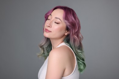 Trendy hairstyle. Young woman with colorful dyed hair on grey background