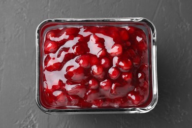 Photo of Fresh cranberry sauce in glass bowl on gray textured table, top view