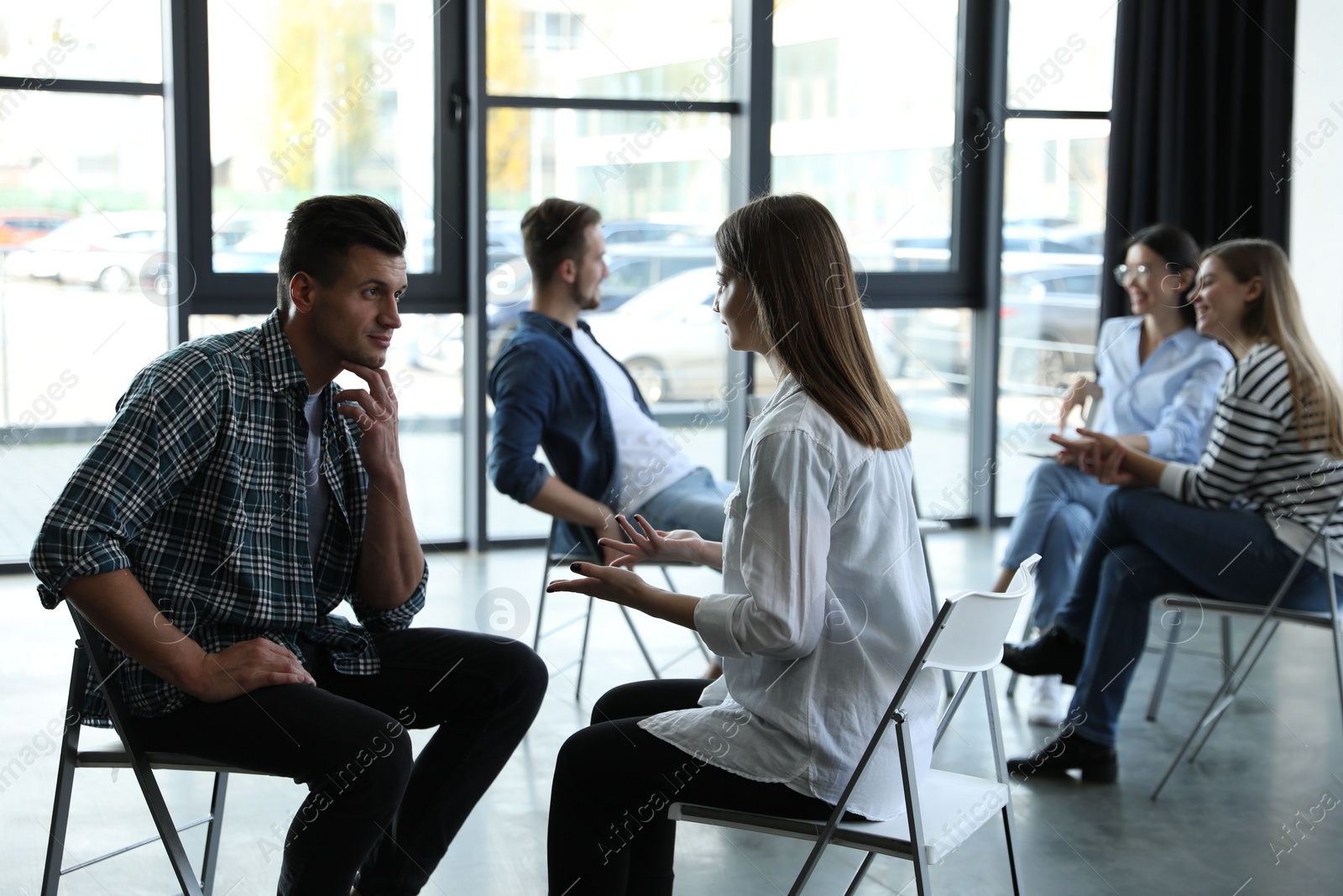 Photo of Psychotherapist working with patient in group therapy session indoors