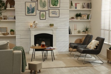 Stylish living room interior with comfortable chairs and decorative fireplace