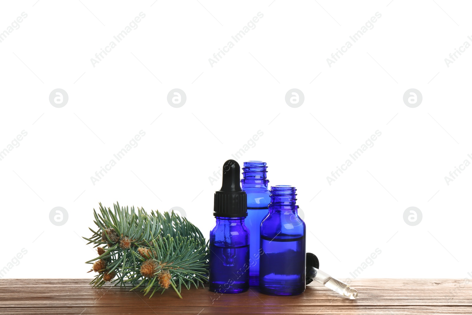 Photo of Bottles of essential oil, pipette and pine branch on table against white background