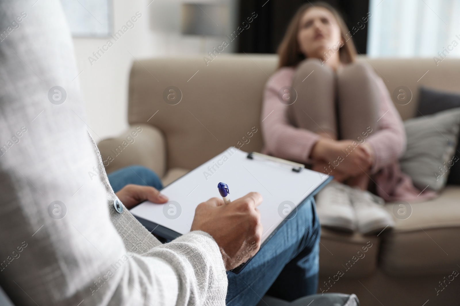 Photo of Professional psychotherapist and patient in office, focus on hands with clipboard