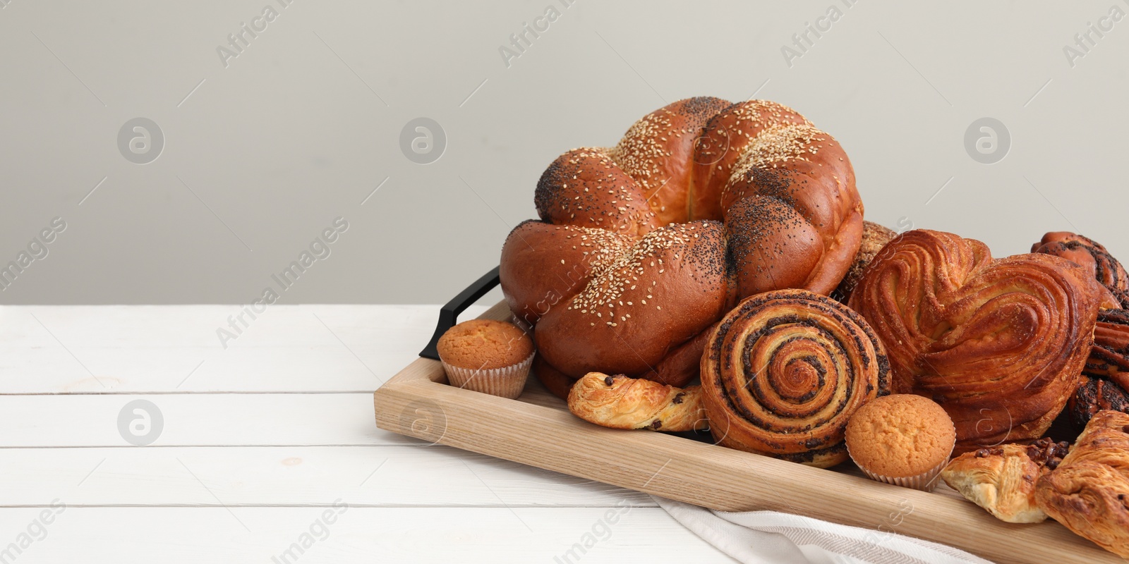 Photo of Different tasty freshly baked pastries on white wooden table, space for text