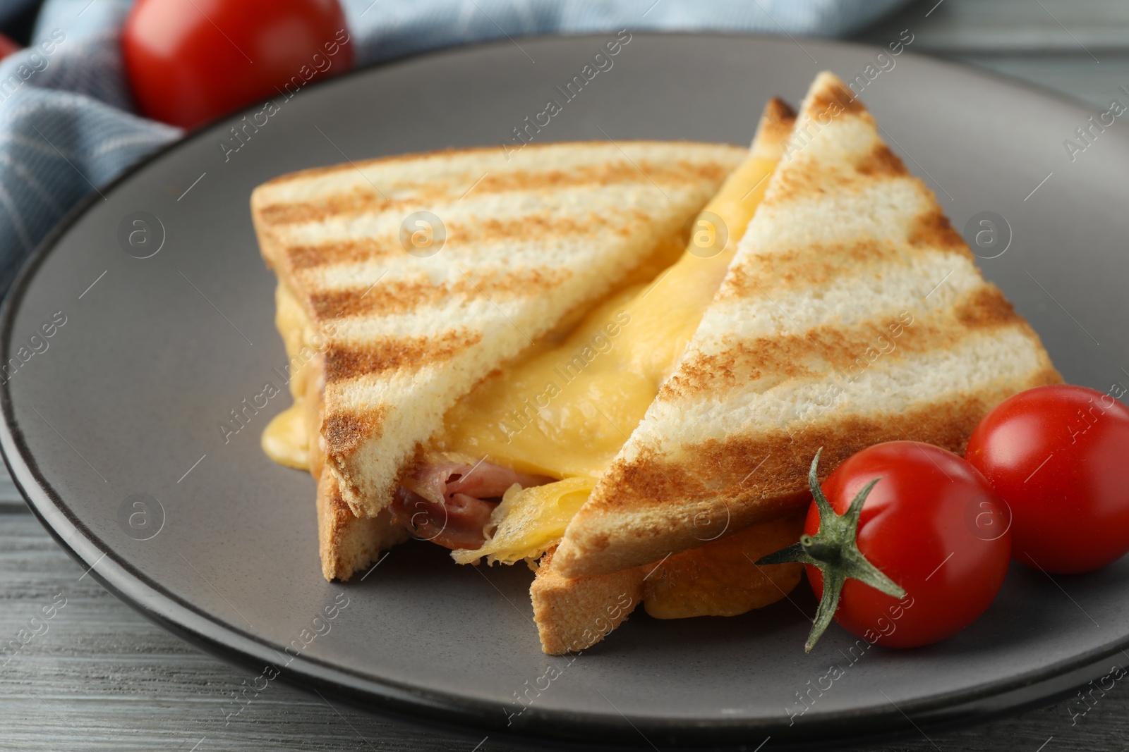 Photo of Tasty sandwiches with ham, melted cheese and tomatoes on grey wooden table, closeup