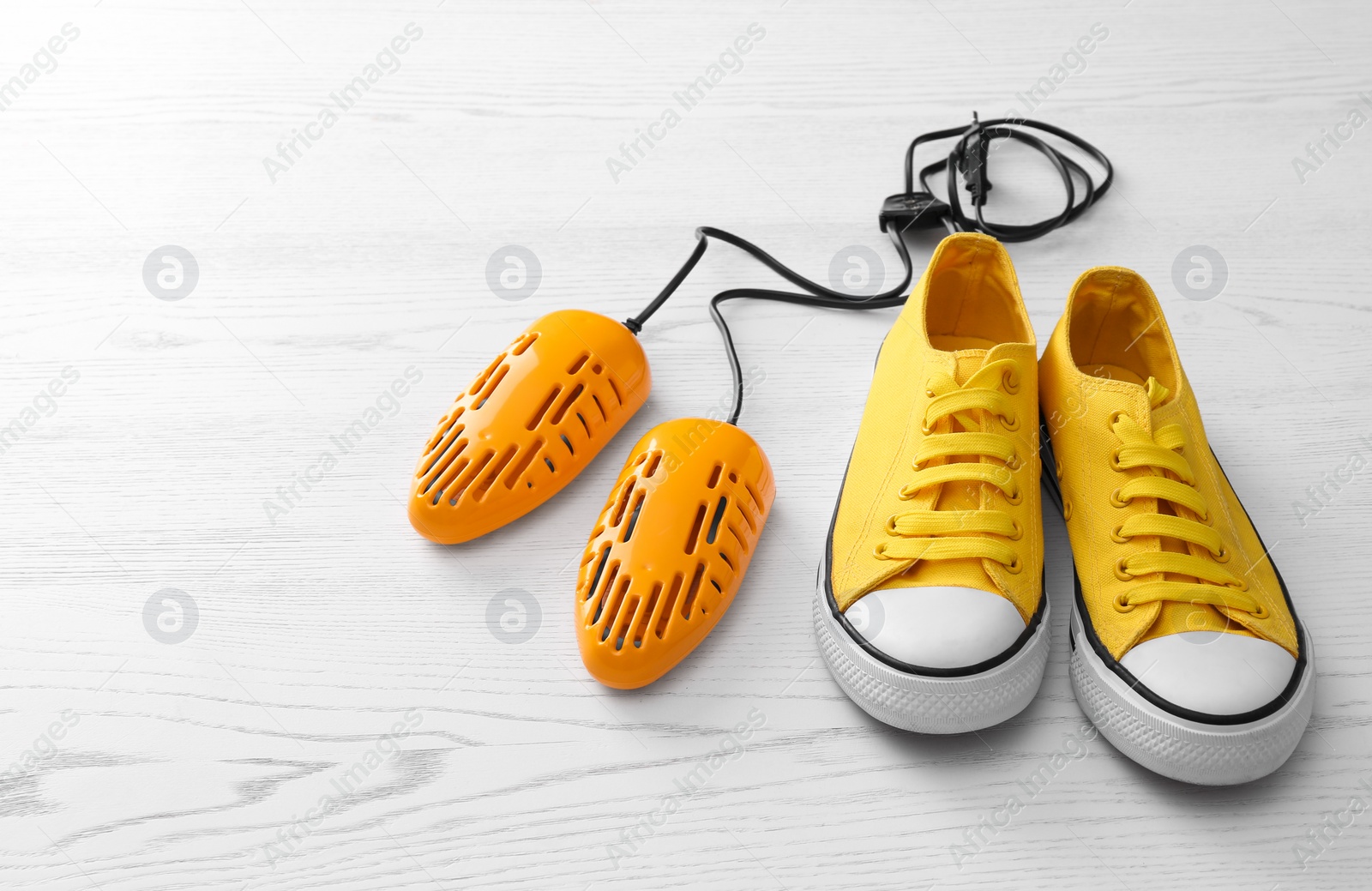 Photo of Shoes and electric dryer on white wooden background