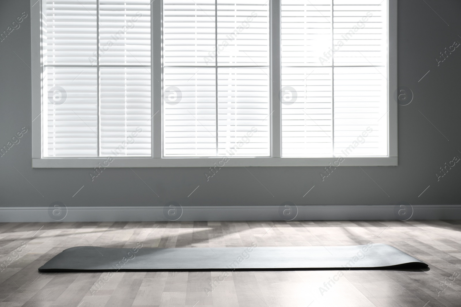 Photo of Unrolled grey yoga mat on floor in room