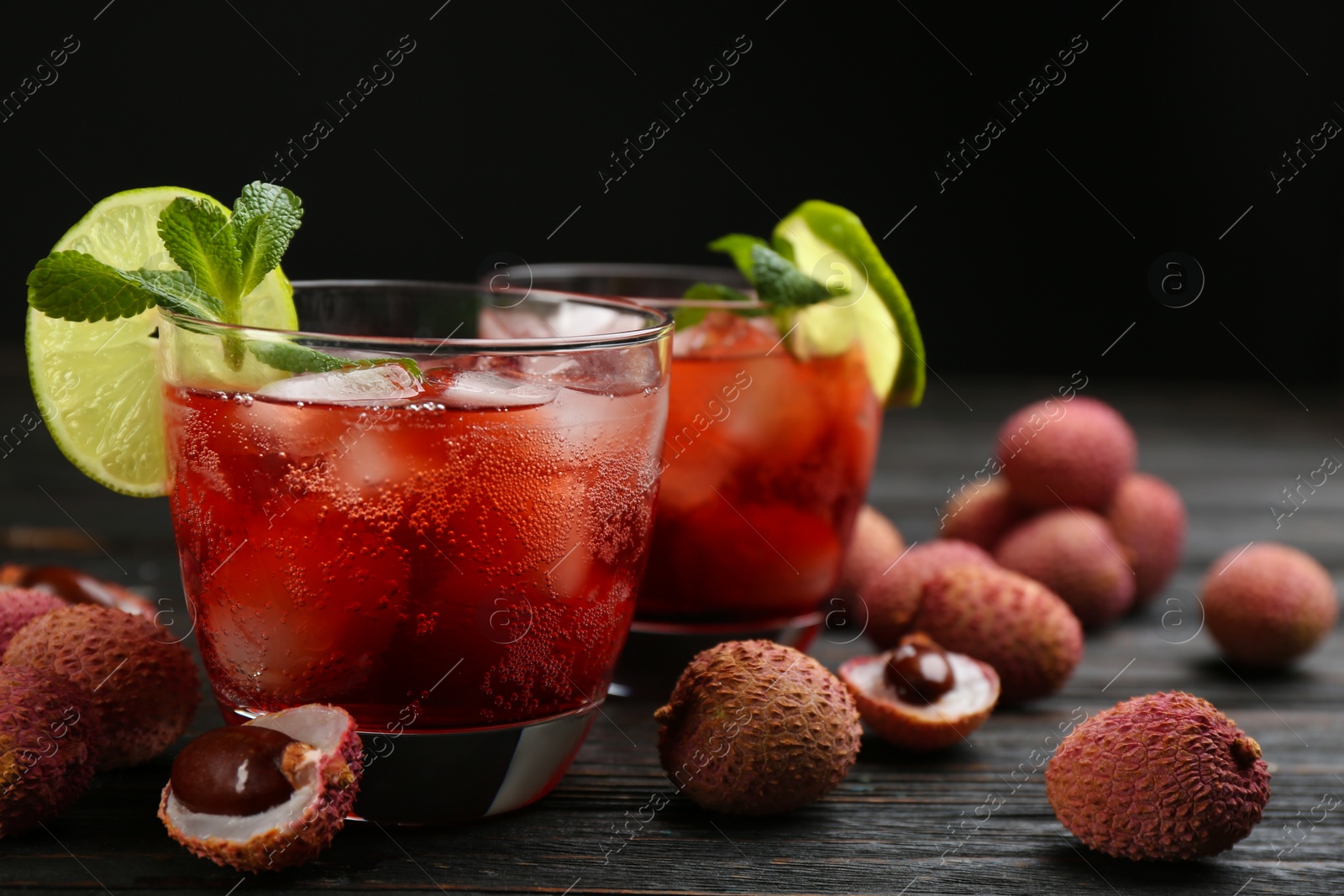 Photo of Lychee cocktail with lime, ice and mint on dark wooden table, space for text