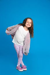 Full length portrait of cute little girl on light blue background