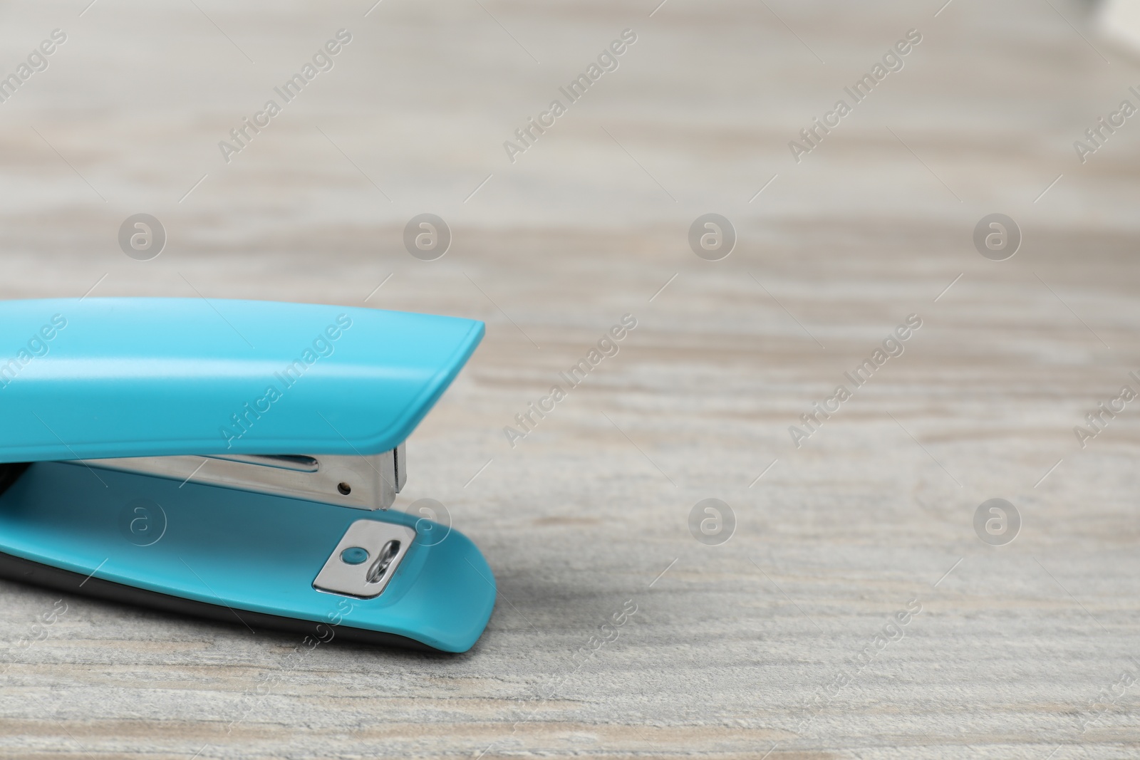 Photo of One light blue stapler on wooden table, closeup. Space for text